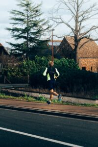 man in black shirt and white shorts running on road during daytime